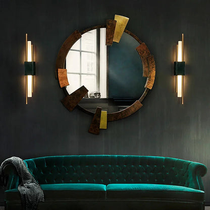 Teal velvet sofa in a room with a large round mirror and wall lights.